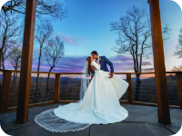 A bride and groom kiss at sunset.