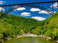 Arched bridge over a green river cutting through two mountains