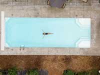 Aerial shot of a woman swimming in a pool on her back