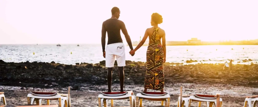 couple holding hands looking over water