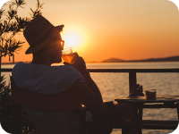 guy with a hat sipping a drink during sunset